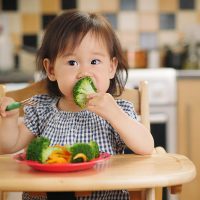 little girl eating vegetables at home