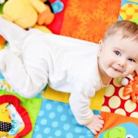 baby playing on colorful playing mat