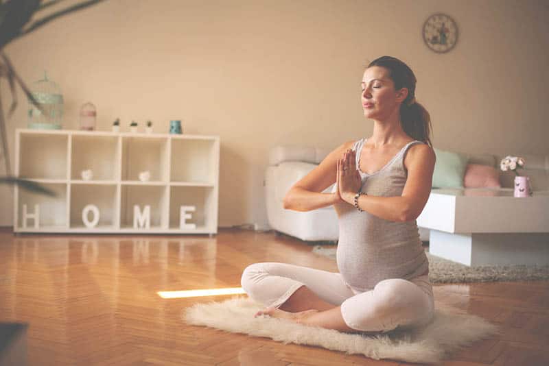 pregnant woman doing yoga in the living room