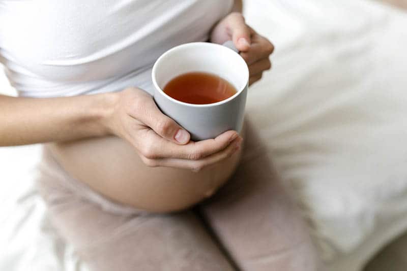 pregnant woman holding a cup of coffee