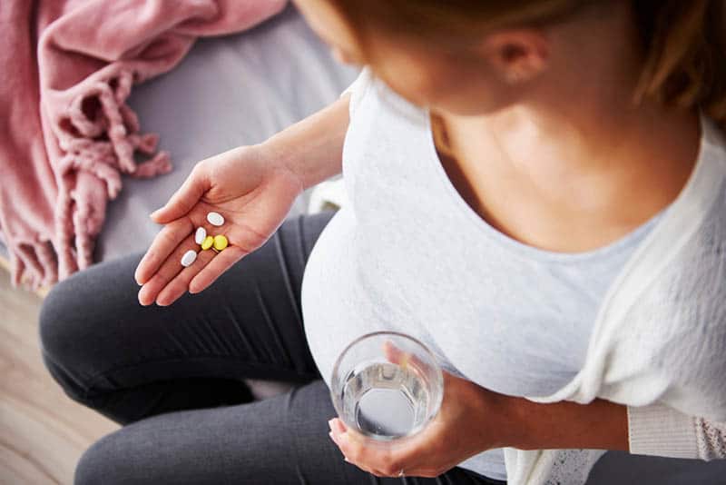 pregnant woman holding pills and glass of water