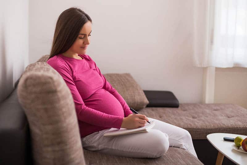 pregnant woman in pink shirt writing a list