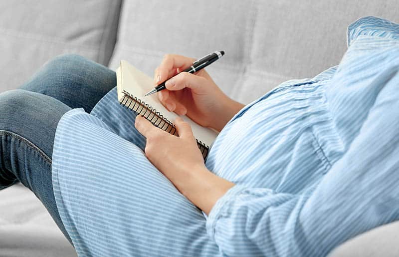 pregnant woman in shirt writing in notes