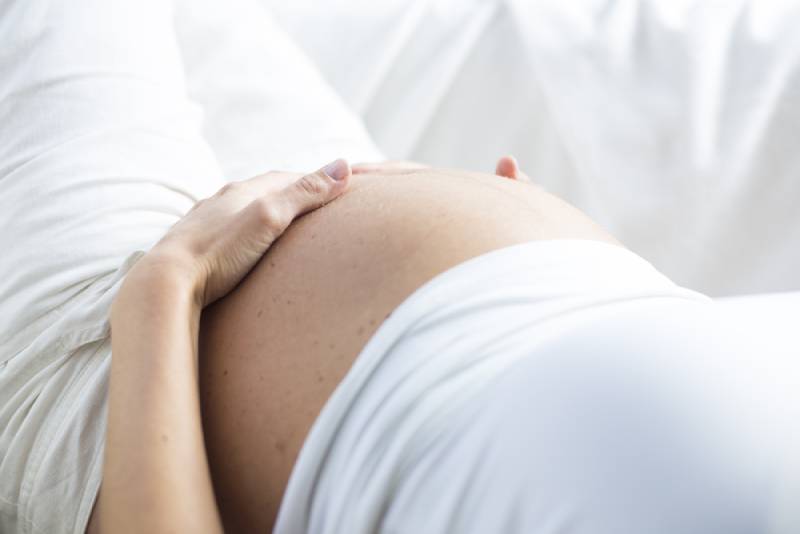 pregnant woman lying and holding her belly