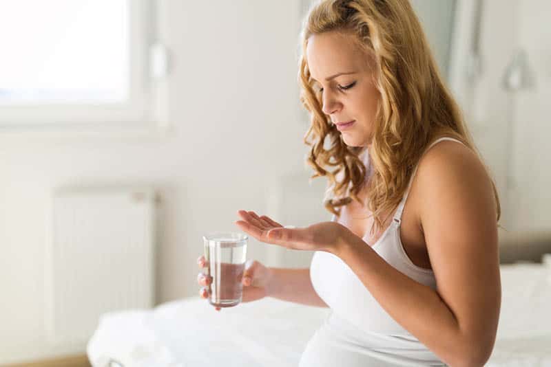 pregnant woman taking a pill against a heartburn