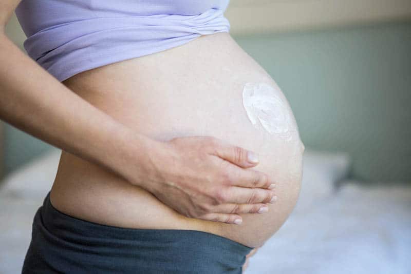 pregnant woman with cream on her belly