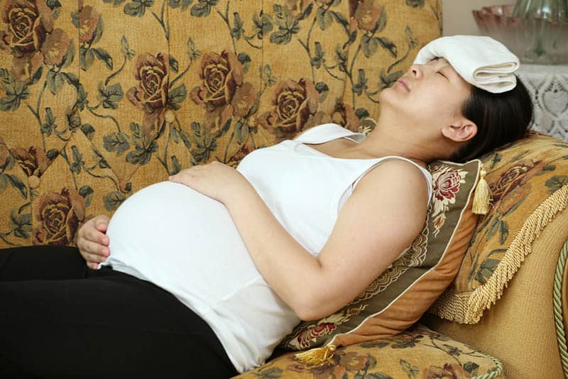 pregnant woman with ice towel on the forehead