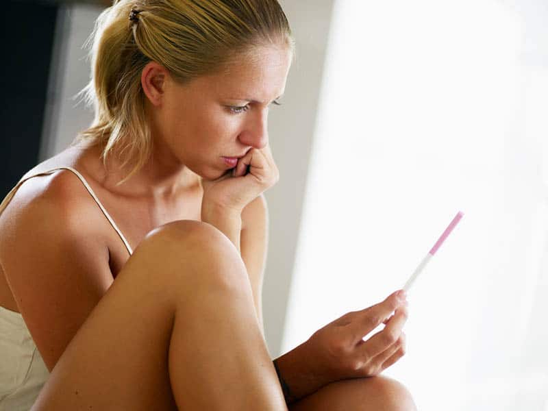 serious woman looking at pregnancy test