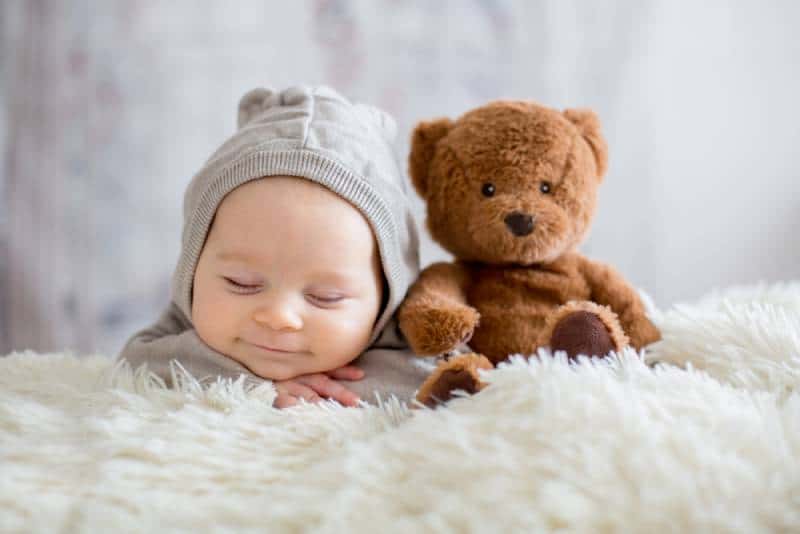 smiling baby boy sleeping with teddy bear