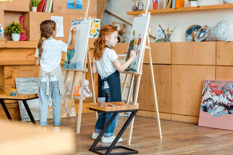 two little girls painting with colors in the room