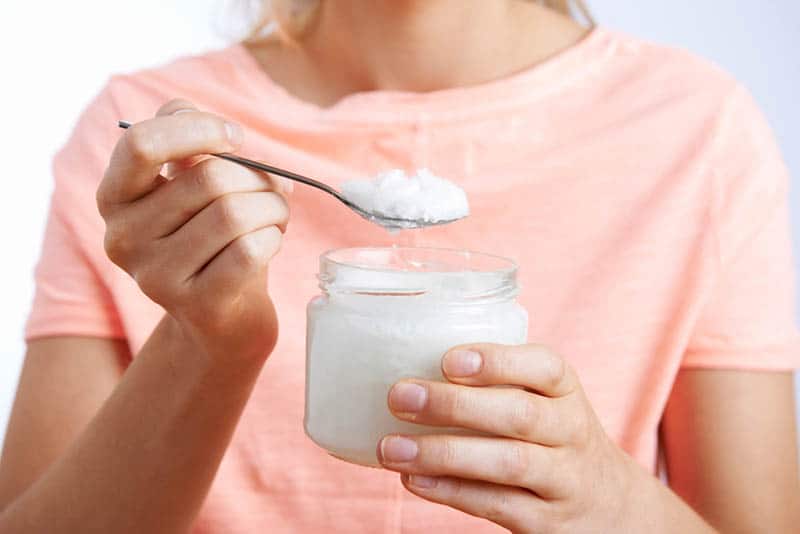 woman holding a spoon full of coconut oil