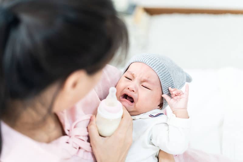 woman trying to feed crying baby