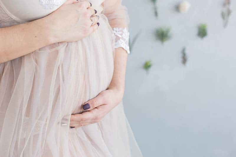 woman with pretty nails holding her pregnant belly