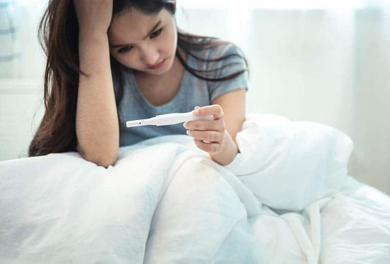 worried woman looking at pregnancy test