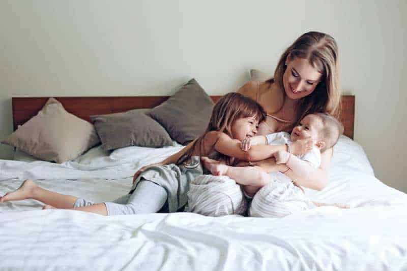 young mother with kids playing on bed
