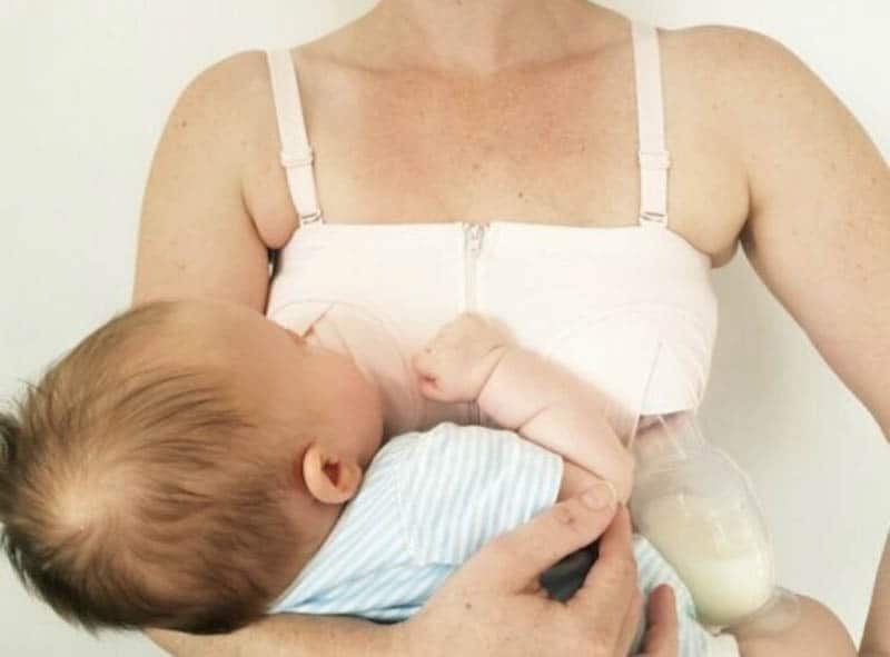young woman holding baby and pumping breast milk