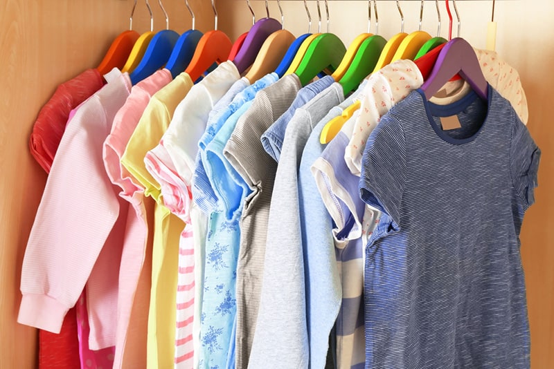 Kid's colorful clothes on hangers in the wardrobe