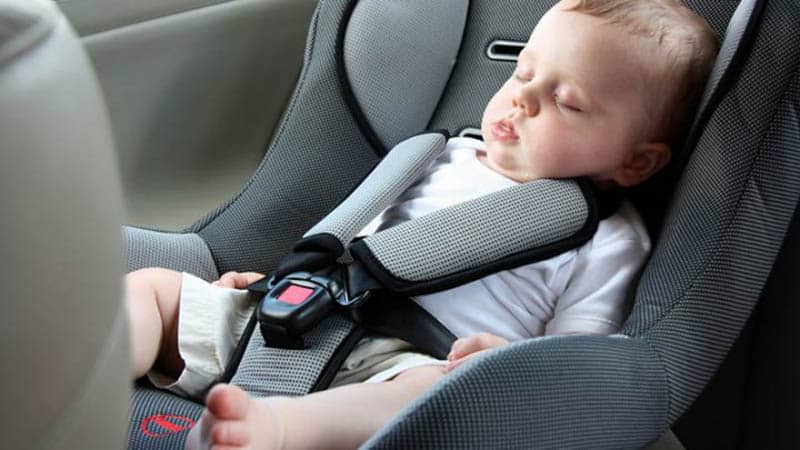 adorable baby boy sleeping in a car seat 