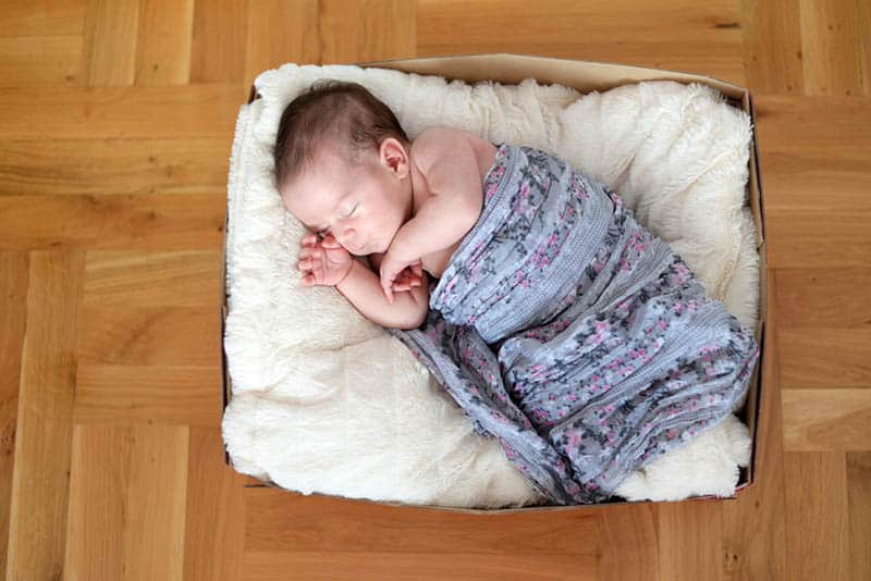 adorable newborn baby sleeping in a cardboard box as a bed