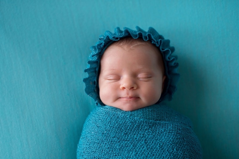 newborn baby boy sleeping wrapped in a blue swaddle