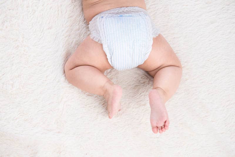 baby in diapers lying on the bed