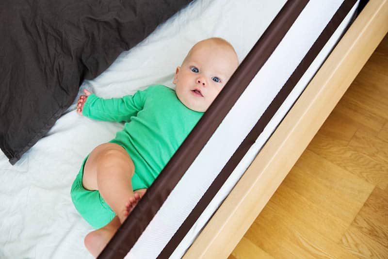 baby lying in bed protected with guard rails