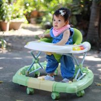 cute baby girl sitting in walker outdoors