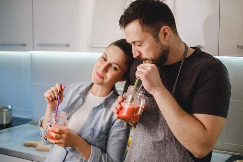 couple drinking smoothies together in the kitchen