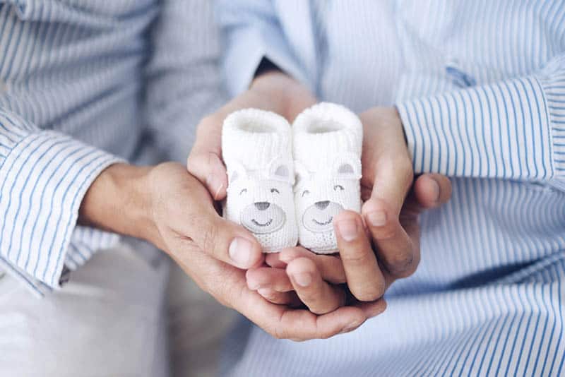 couple in shirts holding cute baby shoes in their hands