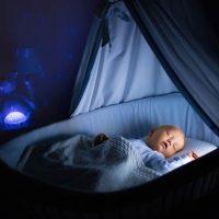 cute baby sleeping at night in a baby bassinet in a room