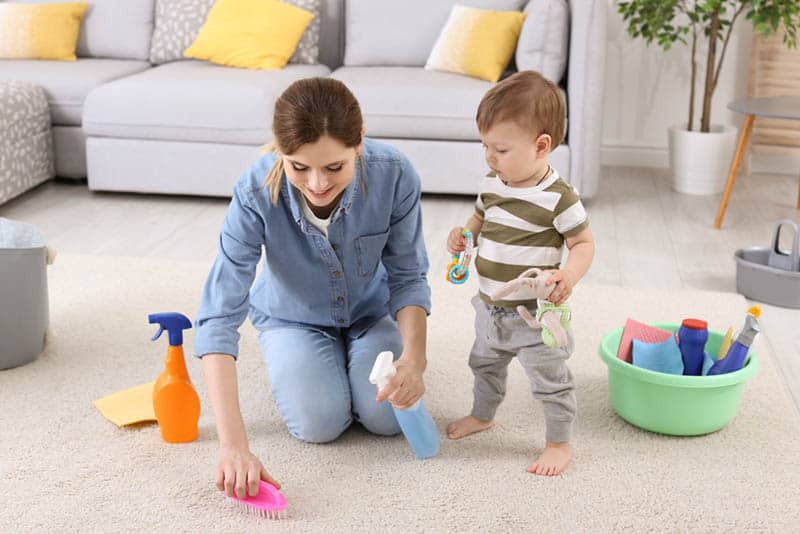cute baby boy helping mother with cleaning