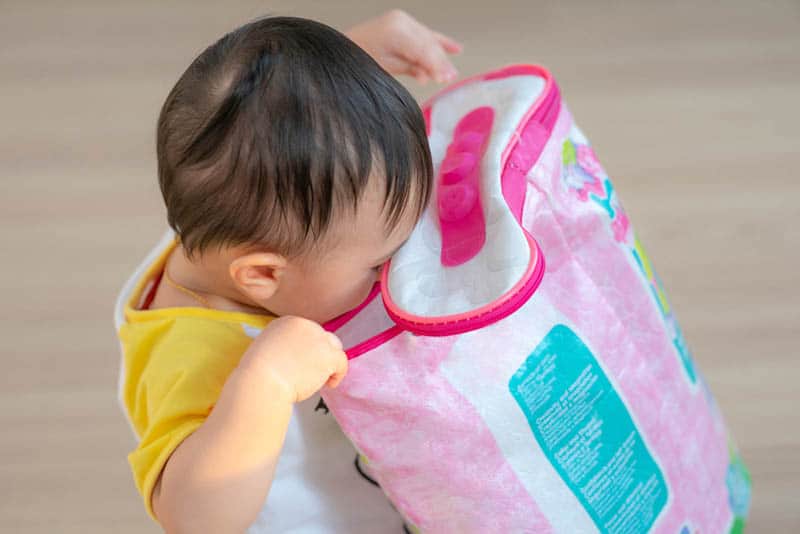 cute baby looking into bag for things to play