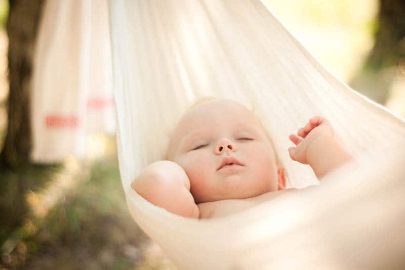 cute baby sleeping tight in a hammock outdoors
