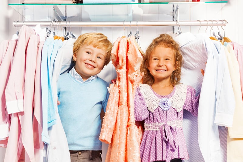cute boy and a girl playing in wardrobe between the kids clothes