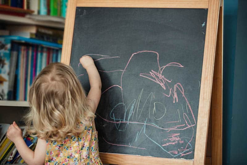 cute little girl drawing with chalk on the board