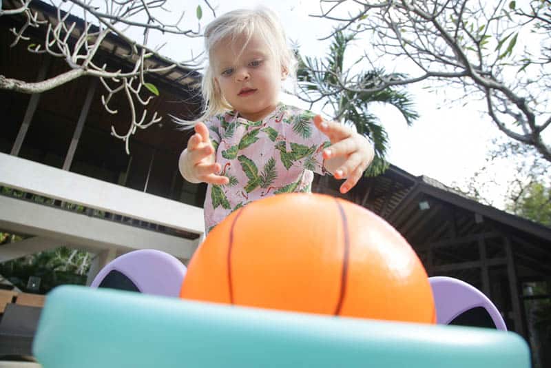 cute little girl playing with plastic basketball ball