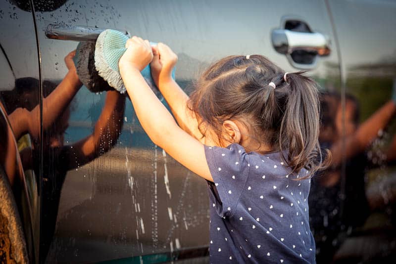 cute little girl washing a car 