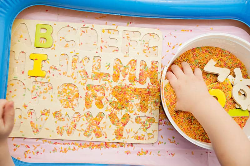 early education for toddlers with colored rice and wooden letters