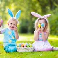 adorable boy and girl playing with easter eggs outdoors