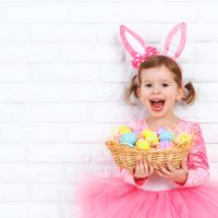 cute baby girl holding easter eggs in a basket