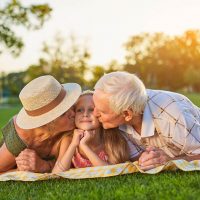 grandparents kissing their granddaughter outdoors