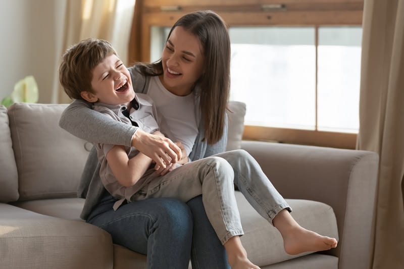 little boy laughing with his mom on the couch