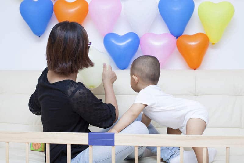 mother and baby boy playing with balloons in the room