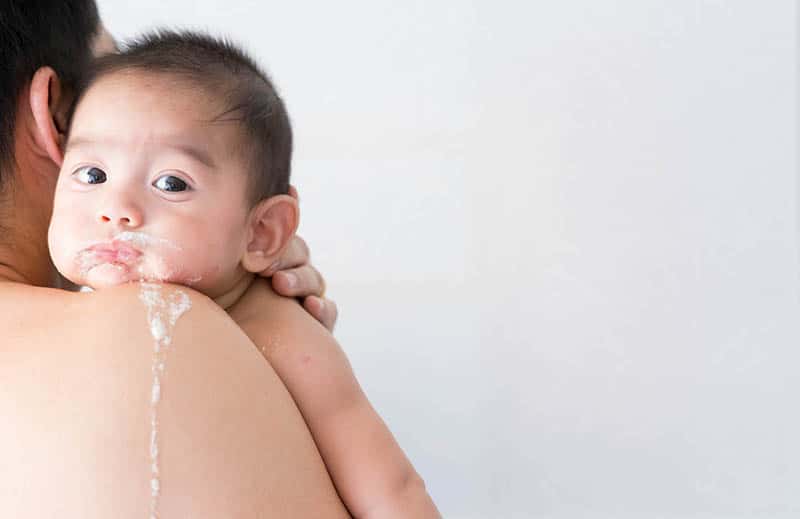 mother holding baby who spits up milk