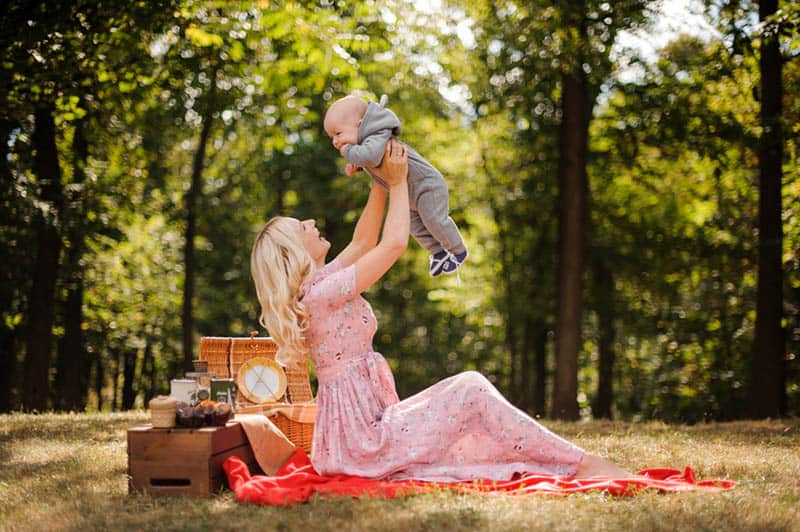 mother playing with baby on picnic in the forest