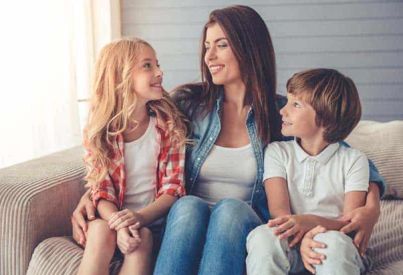 mother sitting with son and daughter on the couch and talking