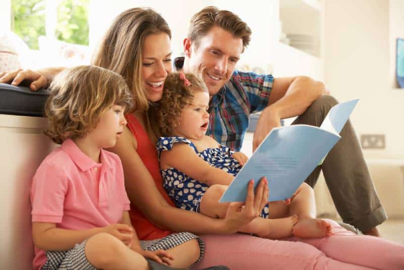 parents reading a book with their kids on the floor