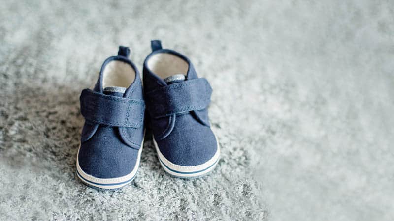 photo of little baby shoes on the grey carpet