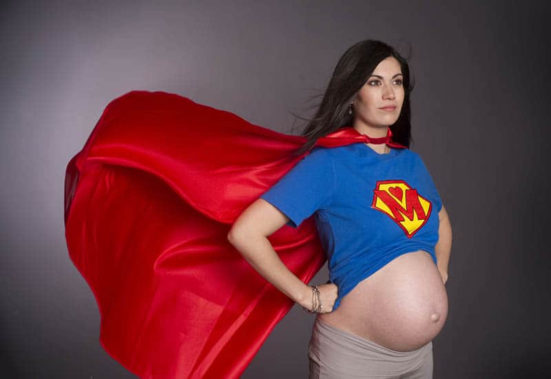 pregnant woman dressed up as superhero with red cape