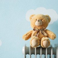 Toy warms to electric heating radiator in blue baby room